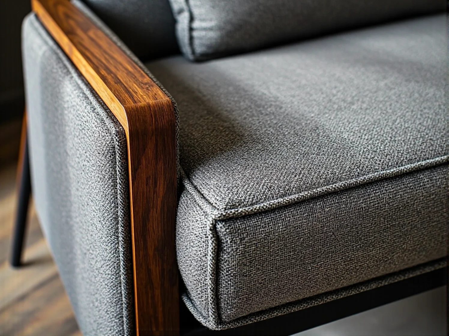 Szary tapicerowany fotel z drewnianymi podłokietnikami orzechowymi