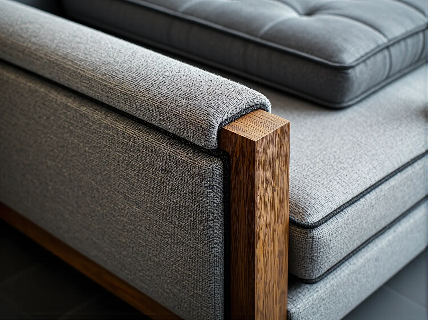 Aranżacja małego salonu w bloku. Szary narożnik dopasowany do ściany z miejscem na stolik kawowy.