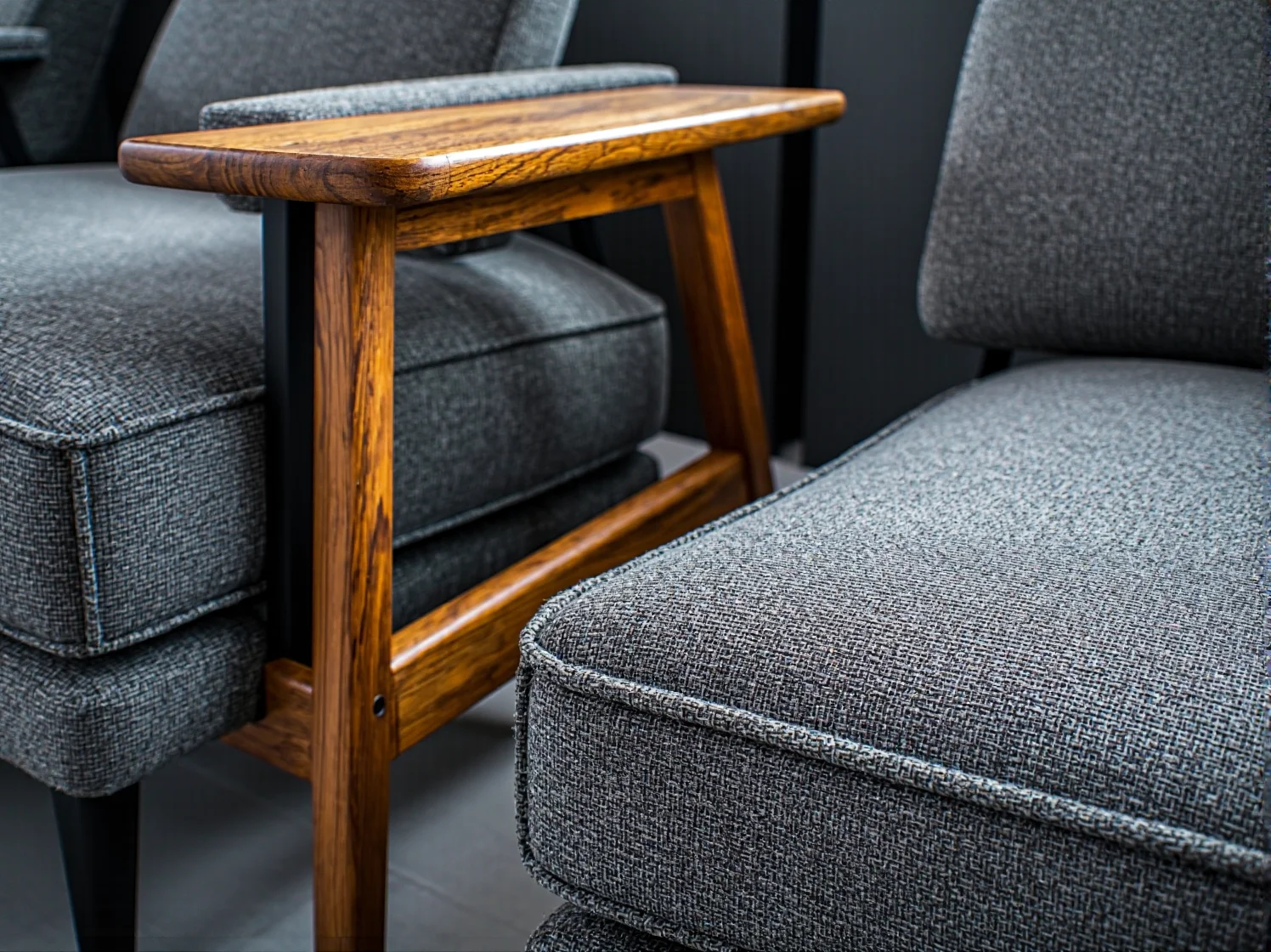 Szary fotel tapicerowany z drewnianym podłokietnikiem dębowym